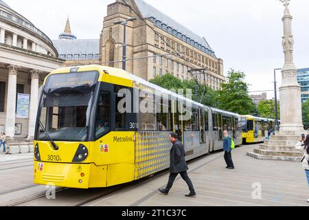 Metropolitana di Manchester, tram pubblico nel centro della città, Inghilterra, Regno Unito, 2023 con biblioteca centrale e edificio del consiglio dietro Foto Stock