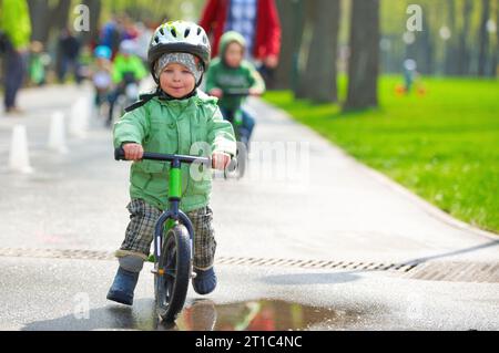 Un bambino che va in bici in una giornata di pioggia Foto Stock