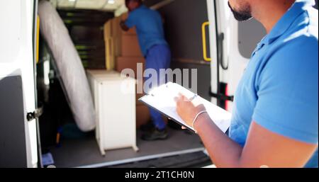 I traslocatori che controllano le caselle di consegna e compilano il documento Foto Stock