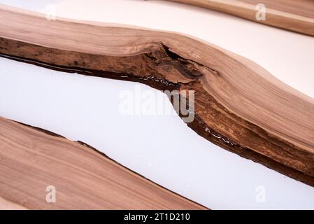 Lavorazione di una tavola in resina e legno artigianale. L'epossidico liquido viene versato in uno stampo con vuoti di legno. primo piano Foto Stock