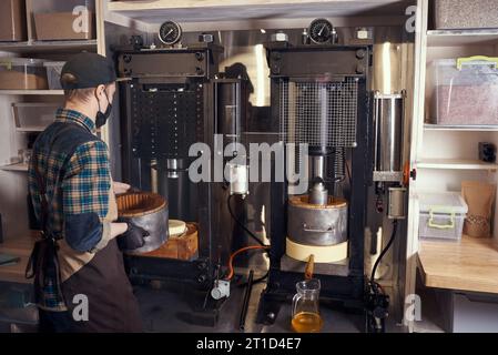 Produzione locale di piccoli oli di semi. Processo di estrazione dell'olio extra vergine di lino fresco. Foto Stock