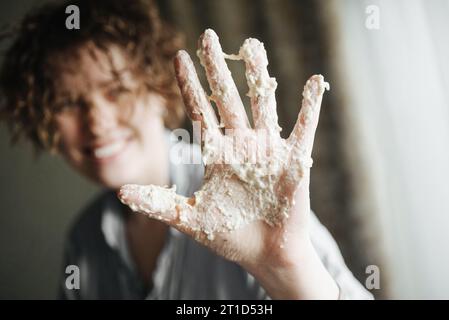 mano ricoperta di pasta, donna sorridente Foto Stock