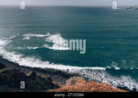 Vista dalla cima della scogliera sul mare con le onde che si infrangono a Tenerife Foto Stock