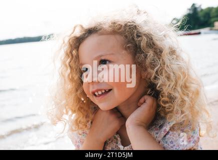 ritratto di un bellissimo bambino sorridente con capelli biondi ricci Foto Stock