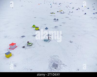 Pesca invernale su un lago ghiacciato. Tende da pesca colorate montate sul ghiaccio del lago. Vista aerea. Foto Stock