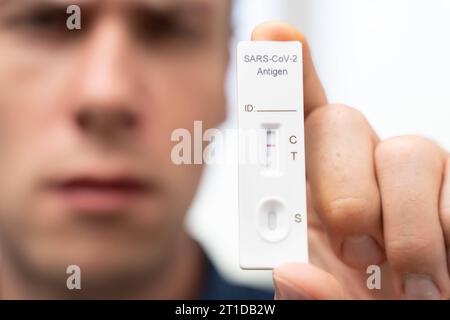 Augusta, Baviera, Germania. 13 ottobre 2023. L'uomo fa un test rapido per il coronavirus Covid-19. Mostra un test con risultato negativo *** Mann macht einen Covid-19 Coronavirus Schnelltest. Er zeigt einen test mit Ergebnis Negativ Credit: Imago/Alamy Live News Foto Stock
