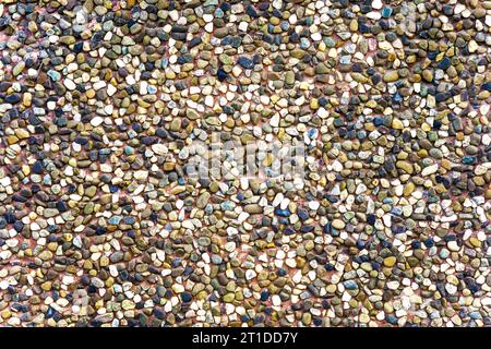 Consistenza di pietre di ceramica marrone. Sfondo marrone dorso di una facciata. Superficie in ceramica. Consistenza di piccole ciottoli scuri colorati. Pavimento in mosaico, co Foto Stock