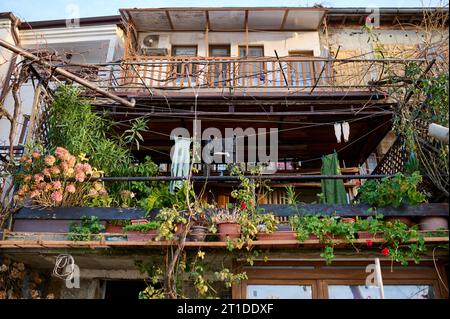 un vecchio balcone in una città costiera con piante e vestiti appesi nessuno Foto Stock