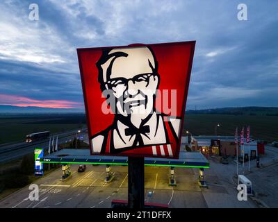 Belozyom, Bulgaria - 24 dicembre 2022 cartello del ristorante fast food KFC presso la stazione di servizio OMV su un'autostrada con vista aerea serale. Foto Stock