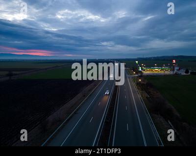 Belozyom, Bulgaria - 24 dicembre 2022 cartello del ristorante fast food KFC presso la stazione di servizio OMV su un'autostrada con vista aerea serale. Foto Stock