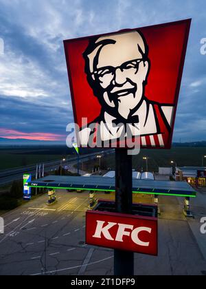 Belozyom, Bulgaria - 24 dicembre 2022 cartello del ristorante fast food KFC presso la stazione di servizio OMV su un'autostrada con vista aerea serale. Foto Stock