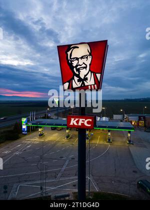 Belozyom, Bulgaria - 24 dicembre 2022 cartello del ristorante fast food KFC presso la stazione di servizio OMV su un'autostrada con vista aerea serale. Foto Stock