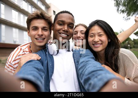 Gruppo di amici allegri e spensierati che fanno un selfie ridendo.i giovani multirazziali si rilassano divertendosi e scattando foto all'aperto. Foto Stock
