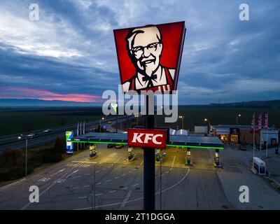 Belozyom, Bulgaria - 24 dicembre 2022 cartello del ristorante fast food KFC presso la stazione di servizio OMV su un'autostrada con vista aerea serale. Foto Stock