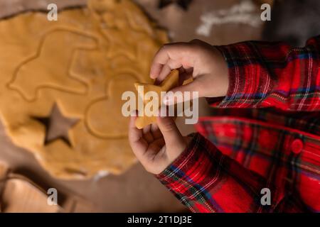 Primo piano delle mani di un bambino che distribuisce la pasta per biscotti per Natale. Foto di alta qualità Foto Stock