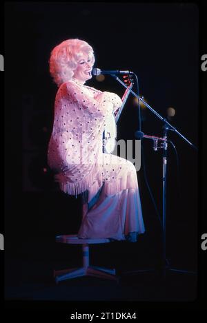 Un sorridente Dolly Parton fa una battuta al suo pubblico mentre tiene il banjo. Da qualche parte nel Midwest nell'estate del 1978. Foto Stock