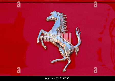 Dettaglio ravvicinato dell'iconico emblema del Cavallino rampante cromato Ferrari che adorna la carrozzeria di una delle loro sportive scarlatte. Foto Stock