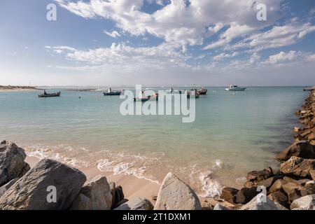 Una scenografia pittoresca si svolge con le colorate barche da pesca ormeggiate serenamente al sole radioso di un porto tranquillo Foto Stock