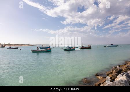 Una scenografia pittoresca si svolge con le colorate barche da pesca ormeggiate serenamente al sole radioso di un porto tranquillo Foto Stock