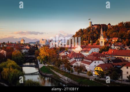 Paesaggio di capitale slovena di Lubiana al tramonto. Castello di Ljubljana sulla collina sopra la città. Fiume Ljubljanica che attraversano il centro città. Caravanche in background. Foto Stock