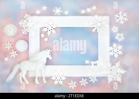 Unicorno di Natale e ornamenti bianchi bauble su sfondo blu rosa cielo cornice bianca. Concetto natalizio per le festività natalizie, biglietto d'auguri, etichetta regalo. Foto Stock