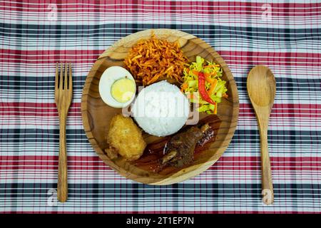 Riso a base di pollo rosso speziato con cetrioli sottaceto e carote, uova sode, frittelle di patate e patate fritte dolci speziate. Foto Stock