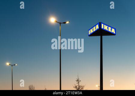 Magdeburg, Germania - 13 dicembre 2022: Cartello con il logo Big IKEA sul pilastro presso il parcheggio dello showroom del punto vendita al dettaglio, in un caldo tramonto blu sera Foto Stock