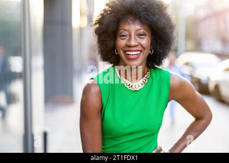 Ritratto di una donna matura che indossa un abito verde in piedi in città Foto Stock
