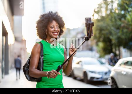 Ritratto di una donna sorridente con il cellulare in città Foto Stock