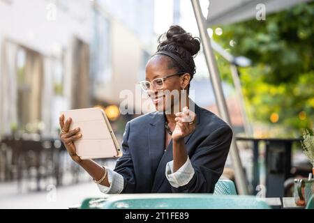 Ritratto di una donna d'affari felice che usa un tablet in una caffetteria all'aperto Foto Stock