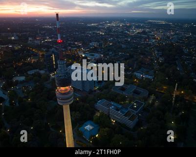 Vista aerea con droni della torre Florian Florianturm a Dortmund di notte, con lo skyline della città sullo sfondo Foto Stock