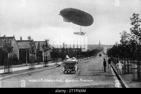 Aviazione in Gran Bretagna prima della Prima Guerra Mondiale l'esercito dirigibile Gamma in volo su Queens Avenue, Aldershot. Un auto è la guida lungo la strada, molti pedoni sono stava guardando il dirigibile. Foto Stock
