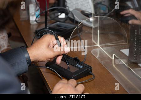 Lo sposo mancino firma il suo autografo sul pad digitale durante una cerimonia civile al municipio. Foto Stock