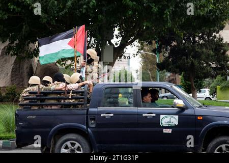 Teheran, Iran. 13 ottobre 2023. I membri della forza paramilitare iraniana Basij, nello stile dei militanti palestinesi e libanesi, detengono una bandiera palestinese durante un raduno pro-palestinese prima delle preghiere del venerdì a Teheran, Iran, venerdì 13 ottobre 2023. (Foto di Sobhan Farajvan/Pacific Press) credito: Pacific Press Media Production Corp./Alamy Live News Foto Stock