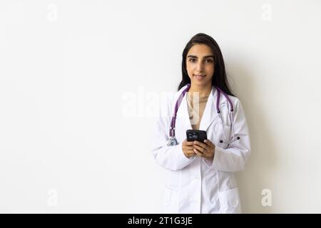 Attraente medico indiano che pongono la donna in uno studio di fronte a uno sfondo Foto Stock