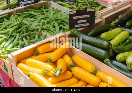 Zucchine verdi e gialle (zucchine) in vendita su una bancarella accanto ai fagioli verdi al mercato all'aperto del sabato ad Arles, Provenza, nel sud della Francia. Foto Stock