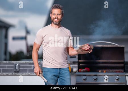 Cuoco alla griglia. Chef con utensili da cucina per barbecue. Barbecue e grill. Picnic e barbecue party. Cuoco capo con utensili per barbecue grill. Barbeque su holid Foto Stock