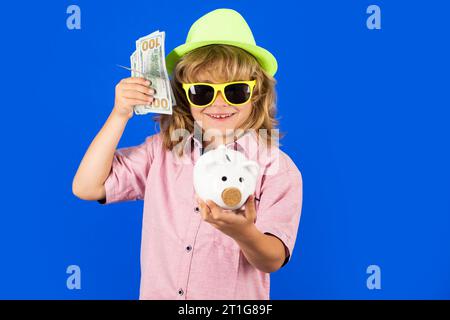 Banconote in dollari e concetto di salvadanaio. Ragazzo che mette moneta nel salvadanaio per risparmiare con una pila di monete. Piggybank con monete e concetto di bambino Foto Stock