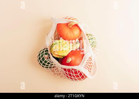 Zucche arancioni in un sacchetto con corda. Concetto di zero rifiuti, cibo sano. Vista dall'alto, base piatta. Foto Stock