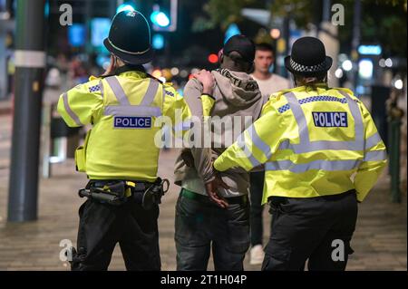 Broad Street, Birmingham, 13 ottobre 2023 - Un uomo viene arrestato per una ragione sconosciuta venerdì 13 - i venditori hanno raggiunto Broad Street a Birmingham venerdì 13 sera. Centinaia di studenti dell'Università di Birmingham vestiti con un abito elegante con il tema di qualsiasi cosa che inizi con la lettera "T" con un gruppo di ragazze che indossano un abito Tampax e un altro gruppo è venuto come un set da tè Tetley mentre festeggiavano la notte a Heidi's Bier bar uno studente si è anche vestito come un tubo di dentifricio e un altro come un "giornale tabloid". Le temperature sono scese a cifre singole con molti che hanno la sensazione di f Foto Stock