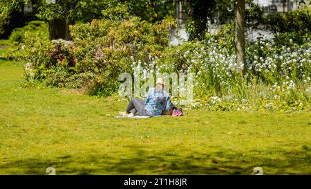 Vista posteriore di una donna anonima seduta in un parco in primavera. Foto Stock