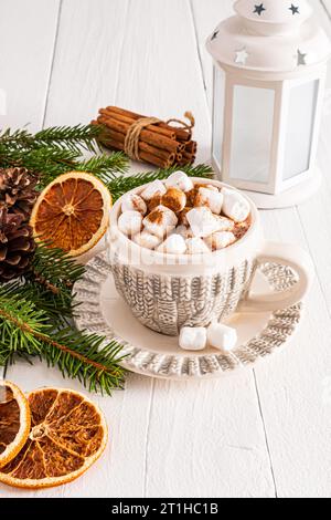 Splendida tazza a maglia con tradizionale bevanda di cioccolata di Natale o cioccolata calda con marshmallow su un tavolo di legno bianco. Vista verticale Foto Stock