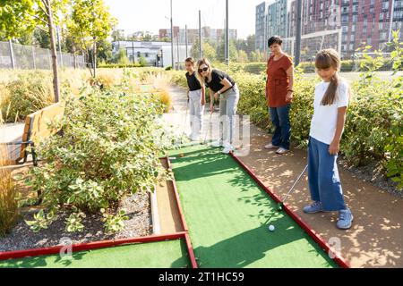mini golf nella natura. un giocatore di minigolf che mette la palla nella buca sulla corsia verde sconnessa. Foto Stock