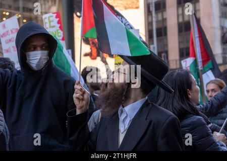 New York, Stati Uniti. 13 ottobre 2023. Un membro di Neturei Karta, un culto anti-sionista ortodosso ebraico, detiene una bandiera palestinese durante una protesta palestinese a Day of Action a Times Square a New York. In tutto il paese e in tutto il mondo, la gente sta organizzando manifestazioni e veglie sia per palestinesi che per israeliani a seguito di un attacco a sorpresa di Hamas il 7 ottobre. L'attacco ha portato a un bombardamento di Gaza da parte dell'esercito israeliano e a una possibile invasione terrestre del territorio. Credito: SOPA Images Limited/Alamy Live News Foto Stock