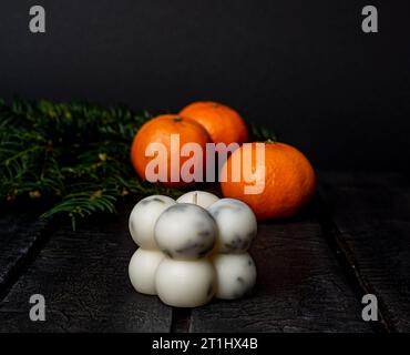 candela bianca e mandarini su sfondo scuro sfocato Foto Stock