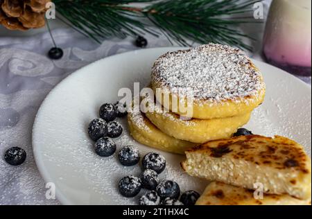 frittelle di formaggio cottage su un piatto bianco con mirtilli su sfondo bianco. vista dall'alto Foto Stock