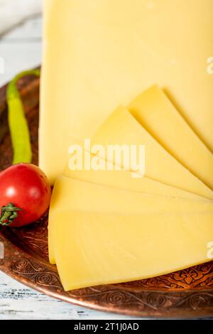 Formaggio stagionato su un piatto di rame. Cheddar di mucca fresco biologico su fondo di legno. Primo piano Foto Stock