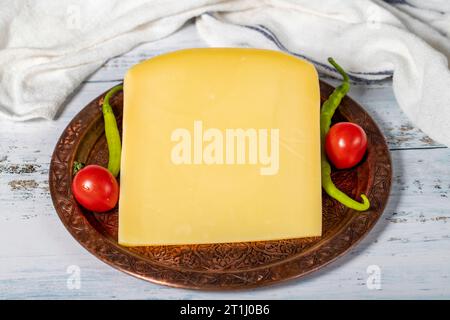 Formaggio stagionato su un piatto di rame. Cheddar di mucca fresco biologico su fondo di legno. Primo piano Foto Stock