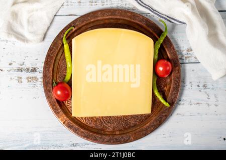 Formaggio stagionato su un piatto di rame. Cheddar di mucca fresco biologico su fondo di legno. Vista dall'alto Foto Stock