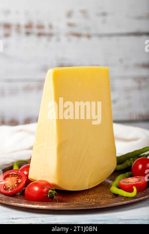 Formaggio stagionato su un piatto di rame. Cheddar di mucca fresco biologico su fondo di legno. Primo piano Foto Stock